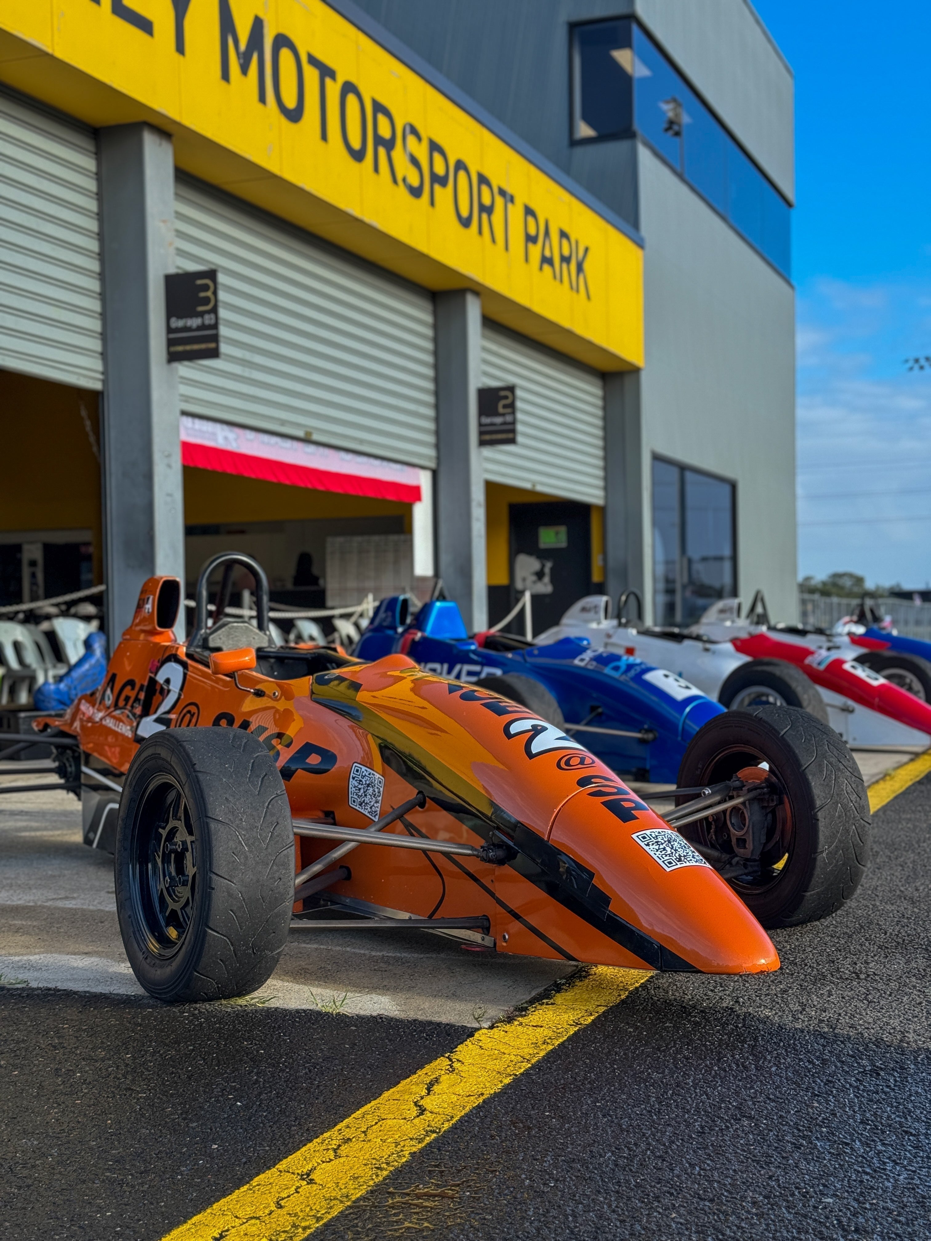 Race cars on display underneath a sign that reads Sydney Motorsport Park